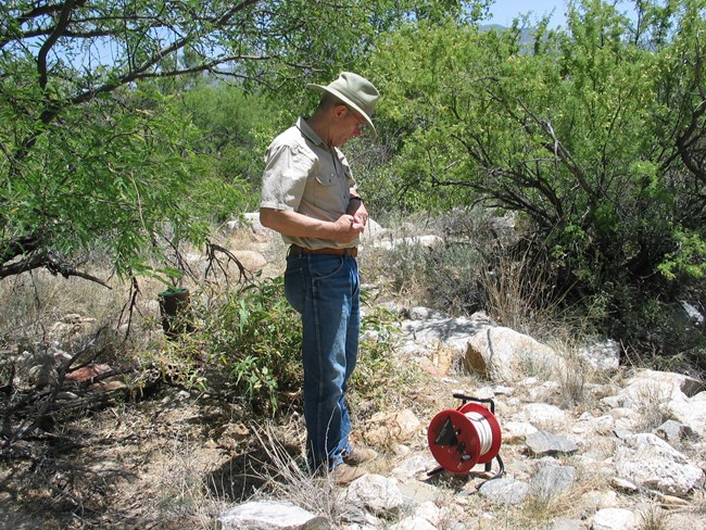 Man standing near a water level meter writes in a small notebook