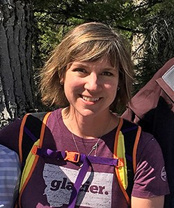 Woman wearing backpack smiles at camera