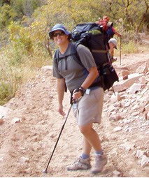 Person with a backpack and hiking pole on a trail