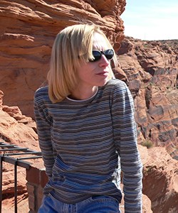 Blonde woman stands in red rock landscape