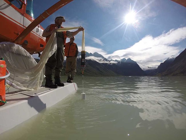 A researcher stands on the floats of a plane to collect water quality information.
