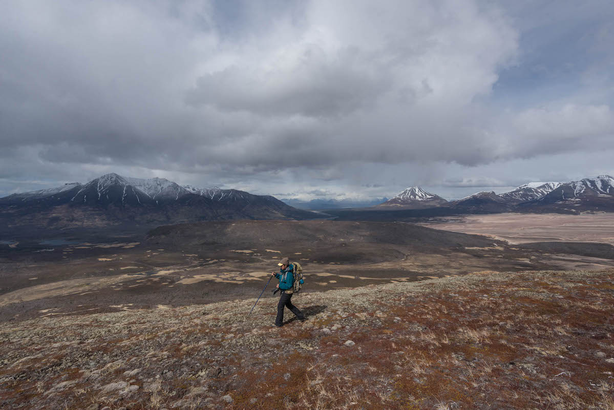 A person walks downhill, a valley in the background