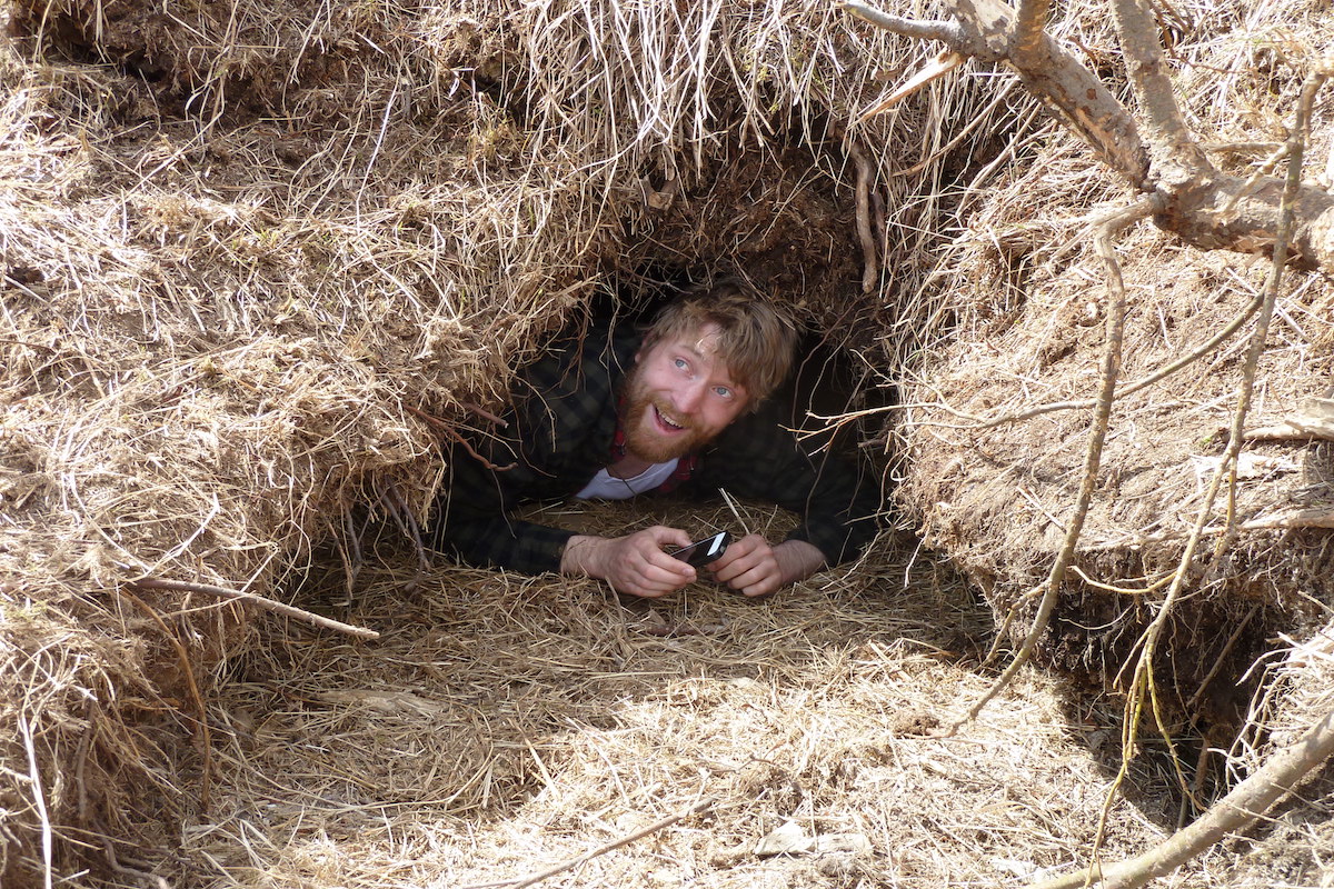 A man pokes his head out from a hole in the earth