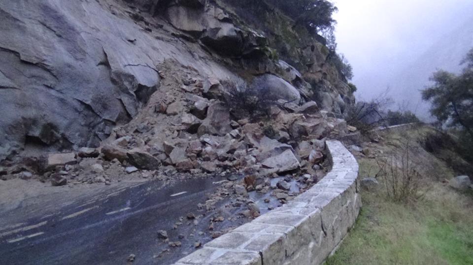 Boulder and rock debris cover a section of a mountain road due to a rain-induced rockfall.