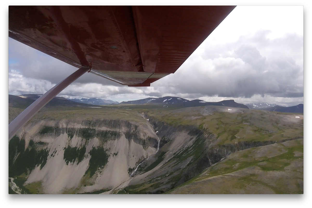 Aerial view of a waterfall and cliffs in the tundra.