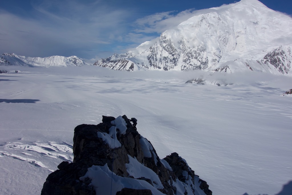 A climber silhouhette nears the top of a rocky outcropping