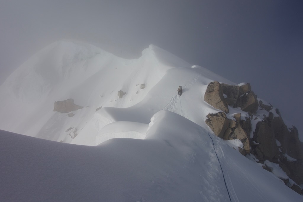 The lead climber ascends a ridge towards the summit