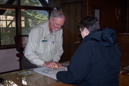 VIP Gordon Seals assists a visitor at the Beaver Meadows Visitor Center (NPS Photo) A volunteer explains the park map to a visitor.