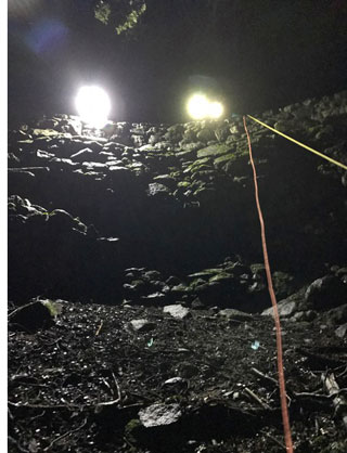 Searchers' spotlights peering down a cliff and wall from above