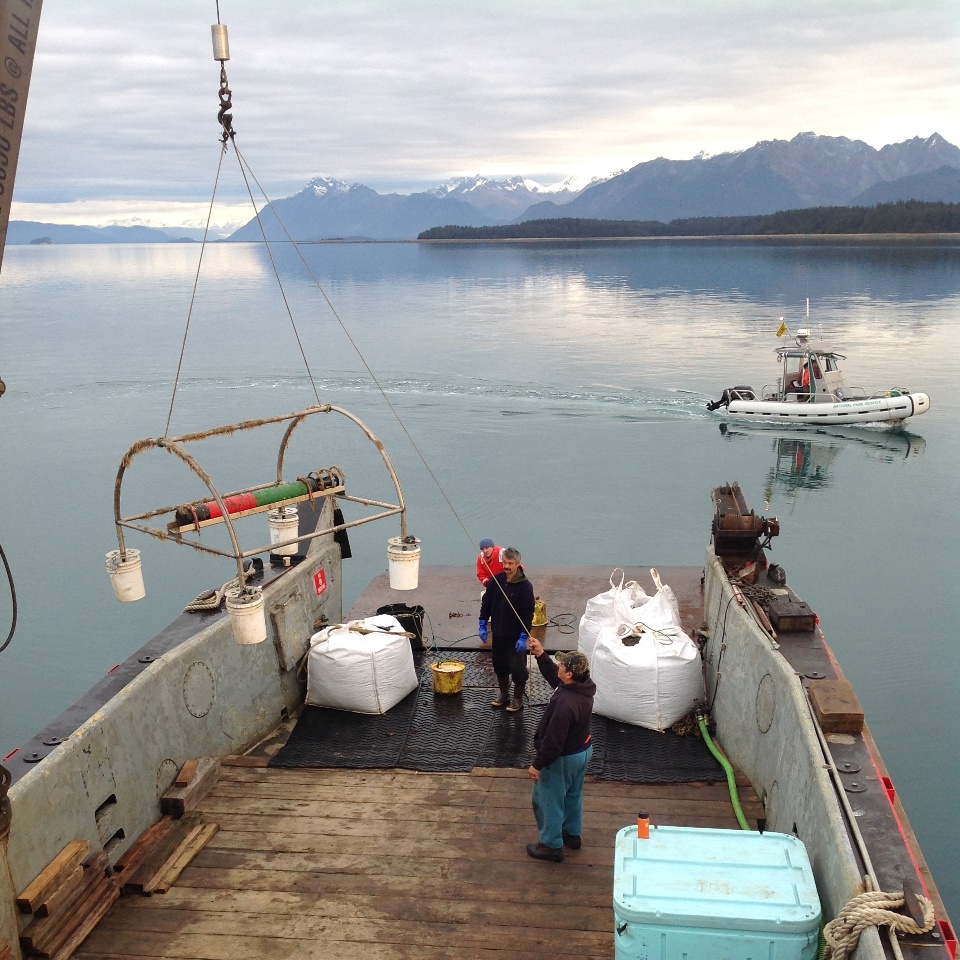 research vessel and crew using a crane to pull recorder out of the ocean