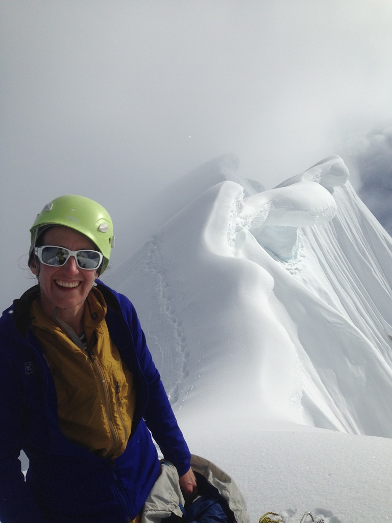 A smiling climber with a dramatic cornice ridge in the backdrop