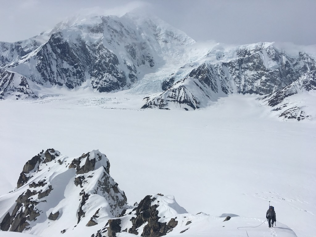 A roped climber descends a snowy ridge line