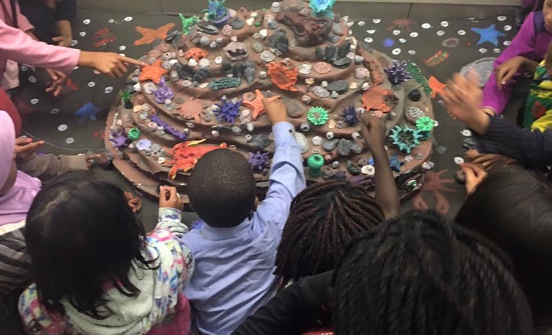 Children creating tidepool model using clay models