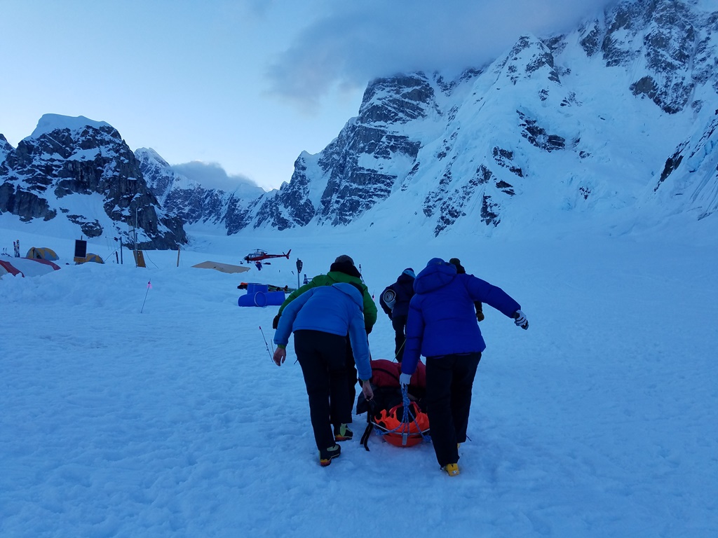 Volunteers help shuttle the appendicitis patient to an awaiting helicopter