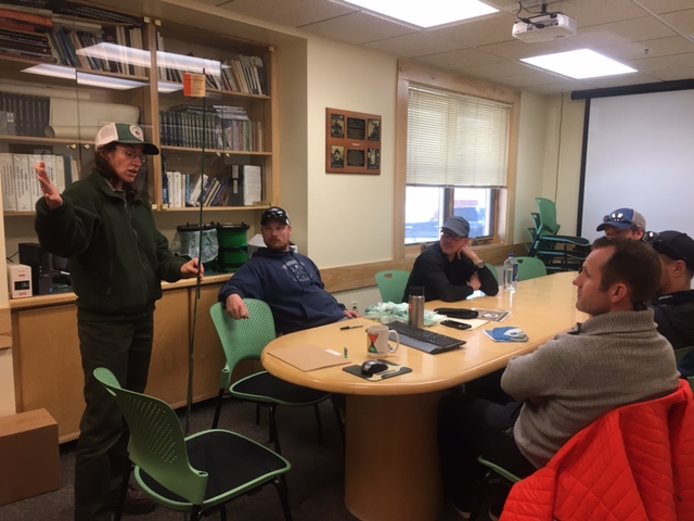 A park ranger speaks to a table full of climbers