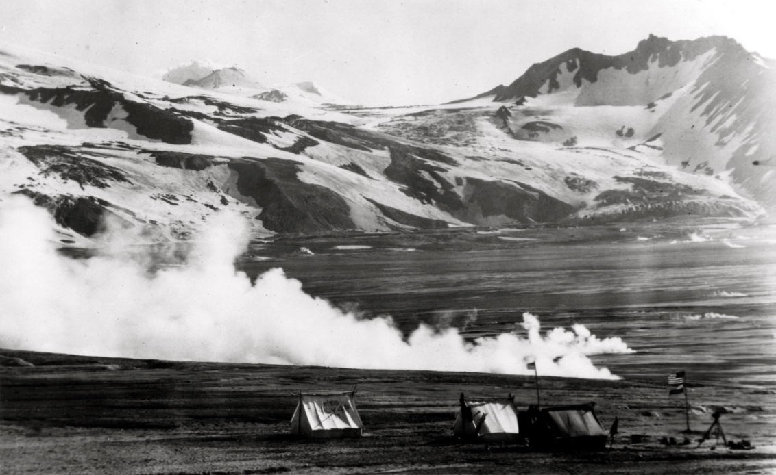 A camp set up next to a steaming vent in a dry valley