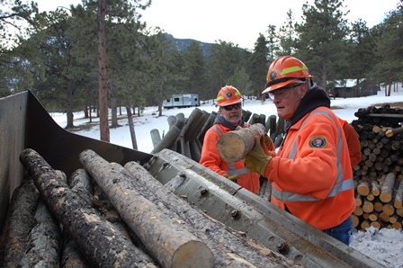 Volunteer Wes TeWinkle loads fence logs into a loader bucket. (NPS Photo / Will Sunderland) Volunteer moving logs into loader bucket.