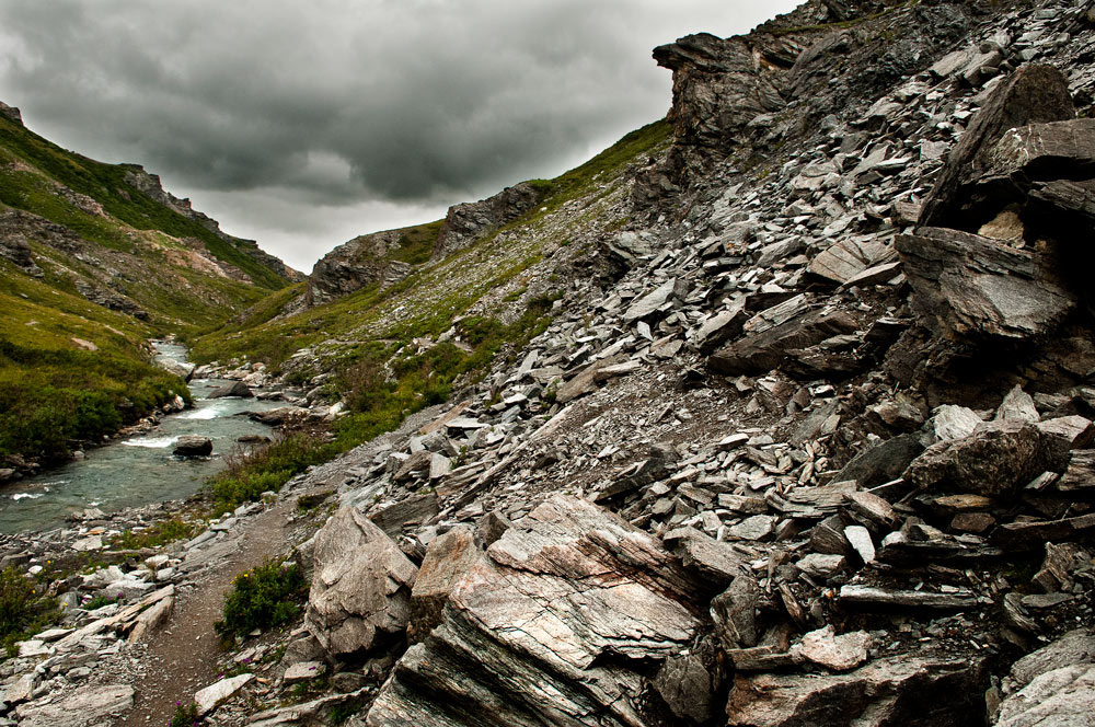 a trail alongside a shallow river in a rocky canyon