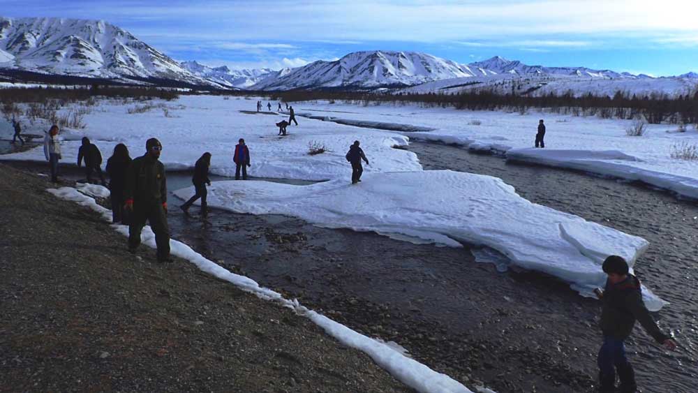 teenagers exploring a shallow, partially frozen river