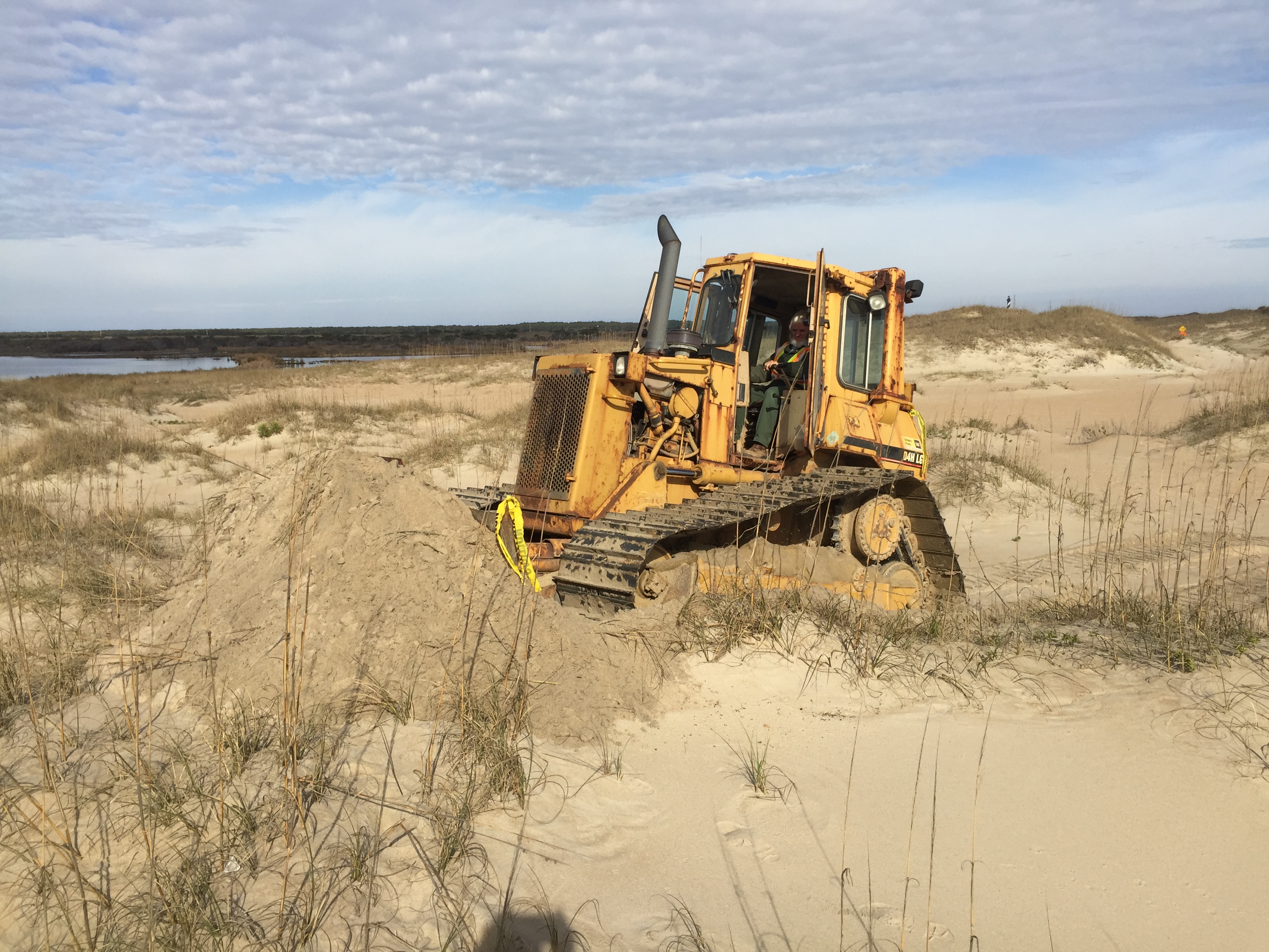 Work on Cape Point bypass started Heavy equipment operator beginning work on Cape Point bypass. Cape Hatteras Lighthouse in background.