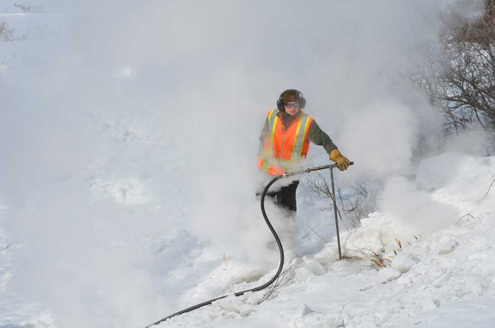 a woman in an orange safety vest and winter clothing surrounded by steam