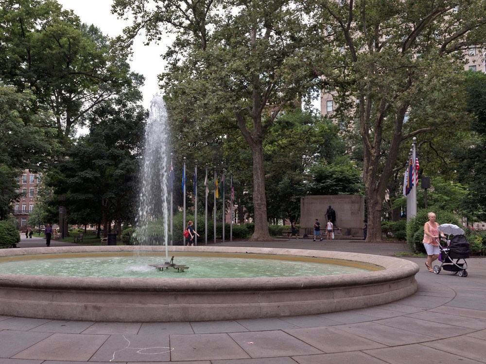 Large circular fountain spraying water into the air with trees in the background