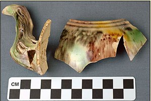 Photograph shows fragments of a ceramic colored teapot.