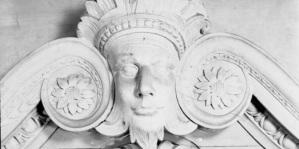 Black and white photo showing close-up of carved mask that looks like a face. Black and white photo showing close-up of carved mask that looks like a face.