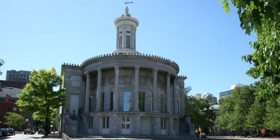 Color photo showing rounded east facade of marble building with many columns.