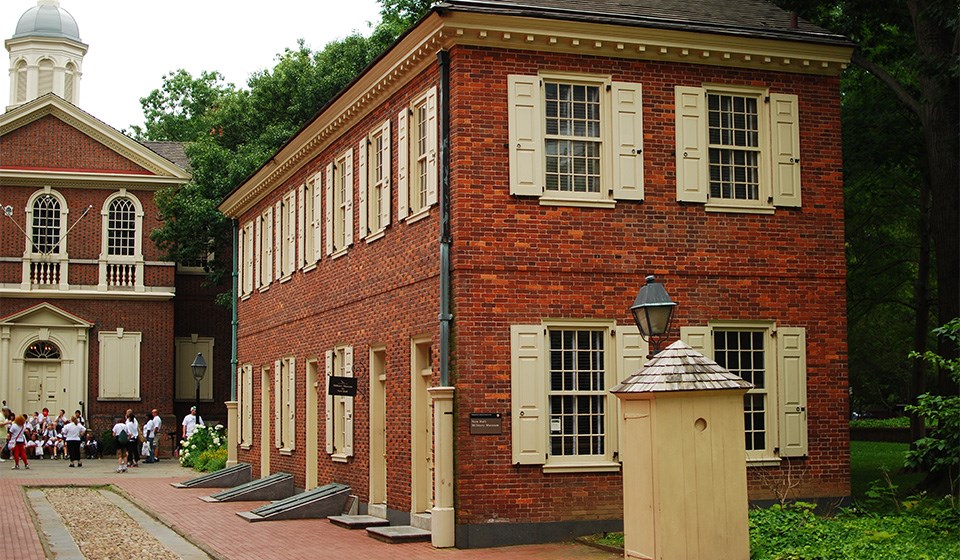 Side view of two story red brick building with cream colored shutters