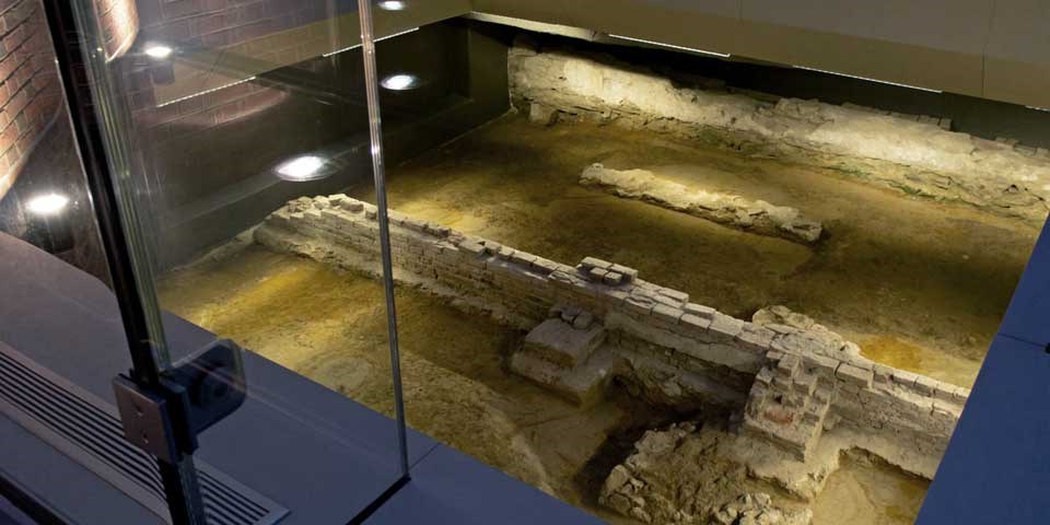 Color photo showing the foundations at the President's House Site, with low brick walls on a dirt floor.