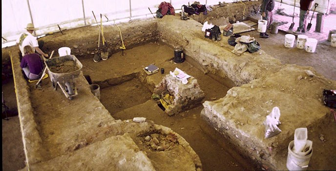 The aerial photograph shows a team of archeologists uncovering archeological features under the tent at the National Constitution Center site.