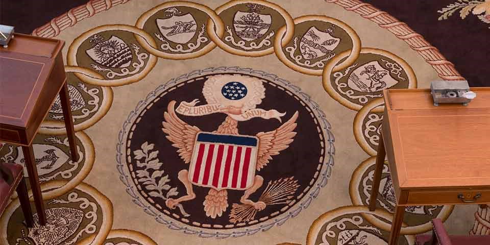 Color photo showing a detail of the Senate carpet, including the Great Seal of the U.S., with a ring of state seals around it.