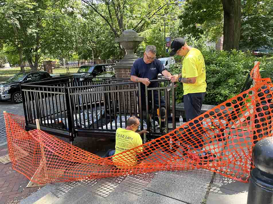 3 workers install black metal ramp on Independence Square. 3 workers installing black metal ramp