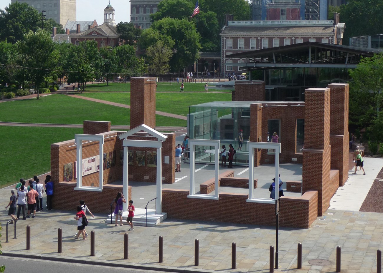 President's House Site Arieal view of waist high red-brick walls and white window frames surrounding a glass cube with archeological remains.
