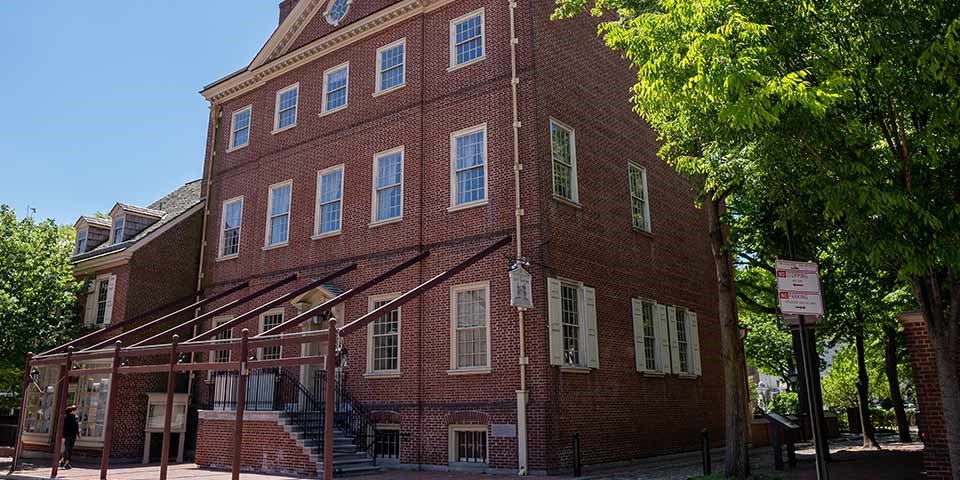 Exterior view of three story red brick building with many windows on each floor.