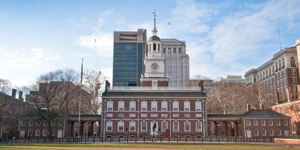 North facade of Independence Hall, showing brick building with many windows and a wooden steeple with a clock face.