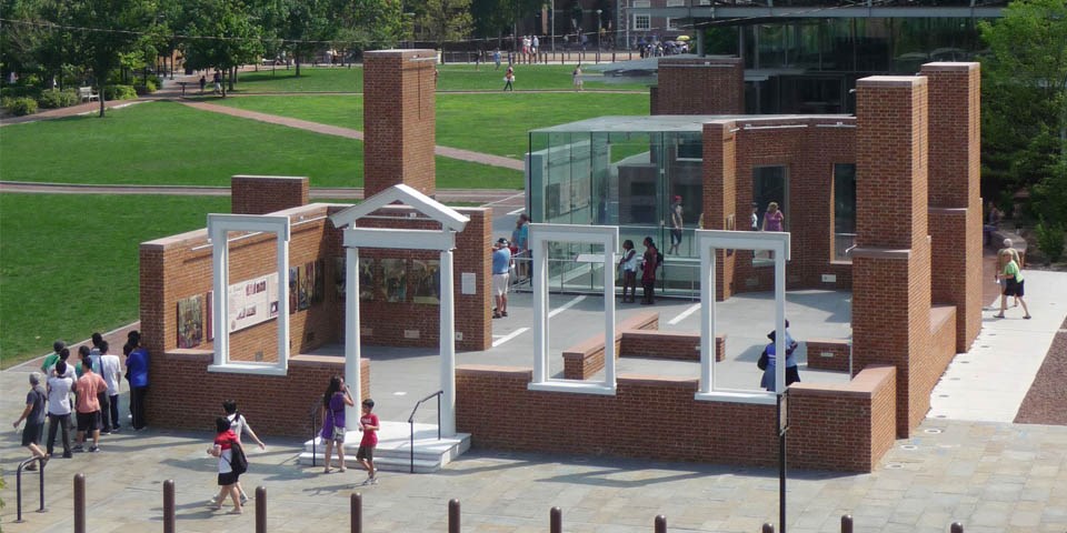 Color photo of President's House Site showing an aerial view of low brick walls, a door, and window frames evoking the feeling of a house.