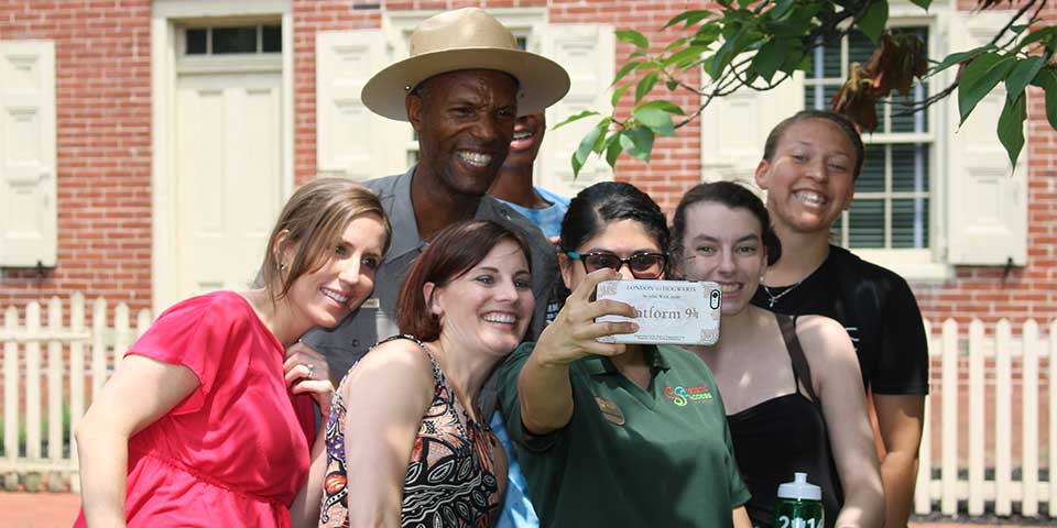 Color photo of a group of women taking a selfie photo with a male ranger. Color photo of a group of women taking a selfie photo with a male ranger.
