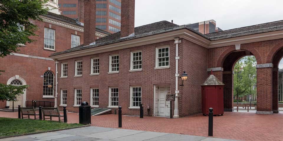 Color photo of the exterior of the West Wing, a two story red brick building with six windows across the top story and five below.