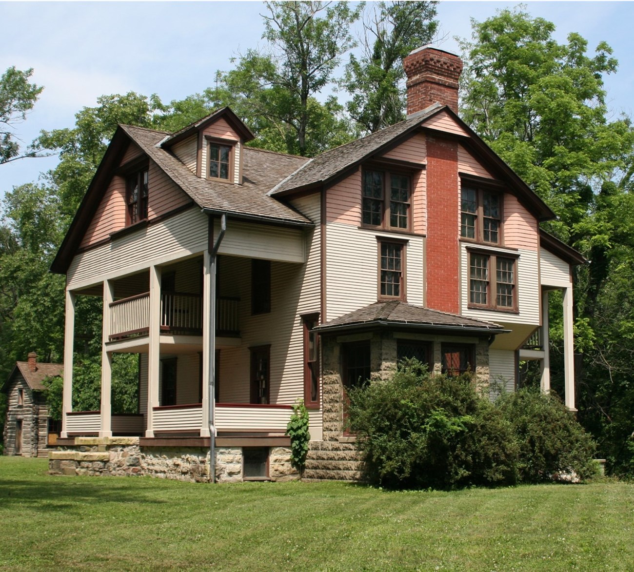 Bailly Homestead Cover The multi-story Bailly Homestead sits on a manicured lawn. The main house has 3 stories and features multi-colored horizontal siding along the upper structure and gray colored stone work along the foundation.