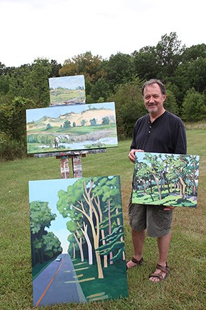 2010 Artist in Residence Victor Pytko standing next to 4 of the 6 paintings completed during his residency.