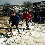young people actively walking up a snow covered dune on snowshoes