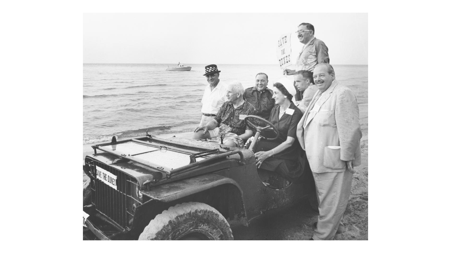 Black and white photograph of a vehicle on the beach. U. S. Senator Paul Douglas, Mayor Richard J. Daley, and Mayor George Chacharis at the Indiana Dunes, 1961