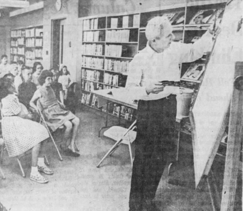 White-haired man demonstrating painting in front of a classroom of students