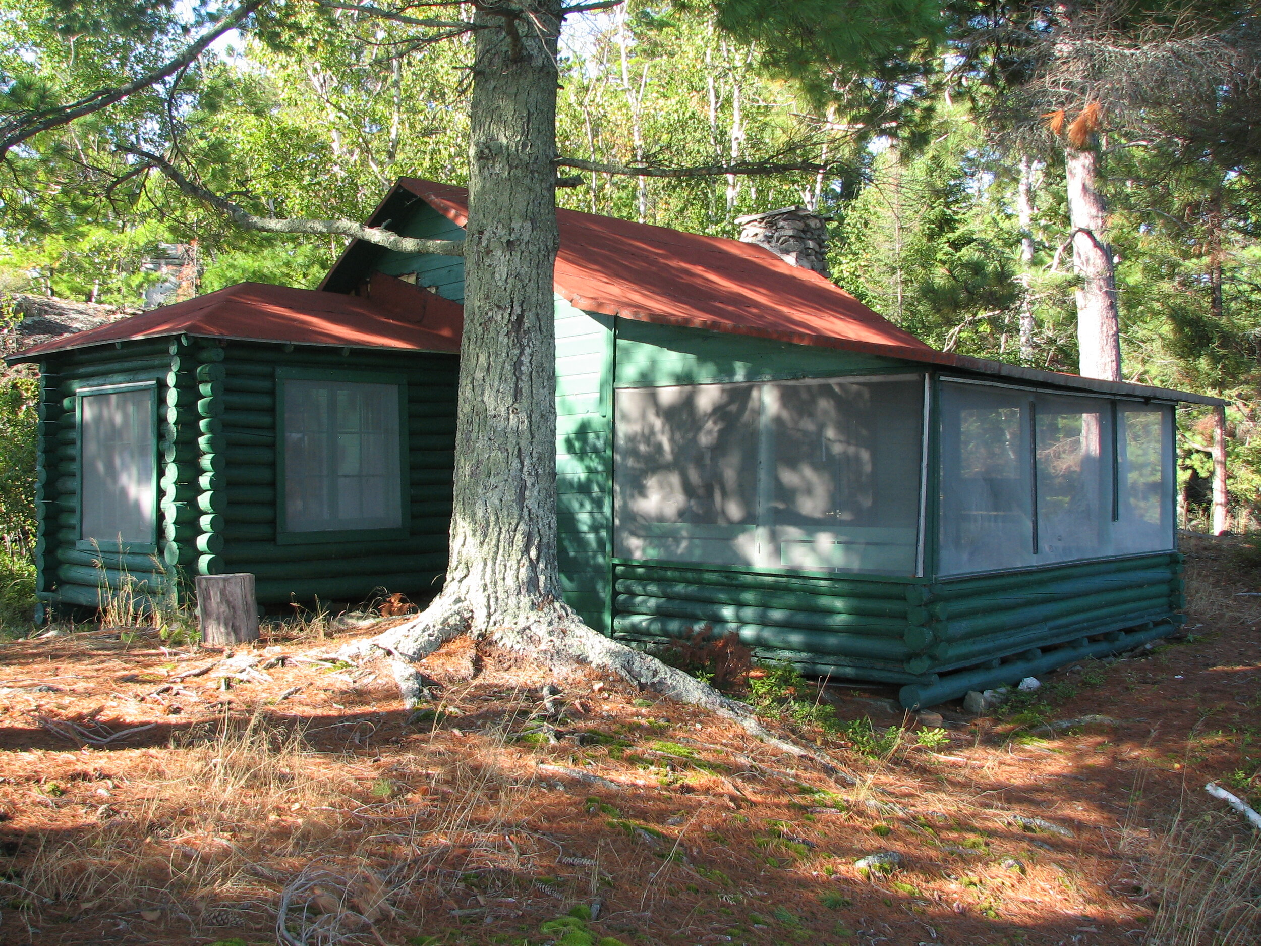 Fujita's cabin at Rainy Lake Photograph of Jun Fujita's Rainy Lake cabin. It has painted green log walls and a light red roof.
