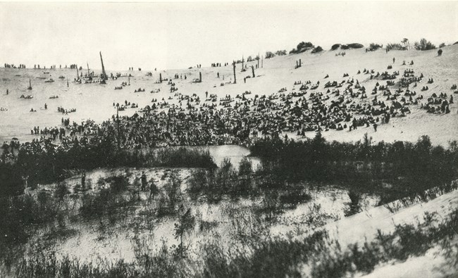 Photograph of the Dunes Pageant, 1917; an audience of people sit in the bowl-shaped depression of a sand dune's blowout to watch a dramataic performance.