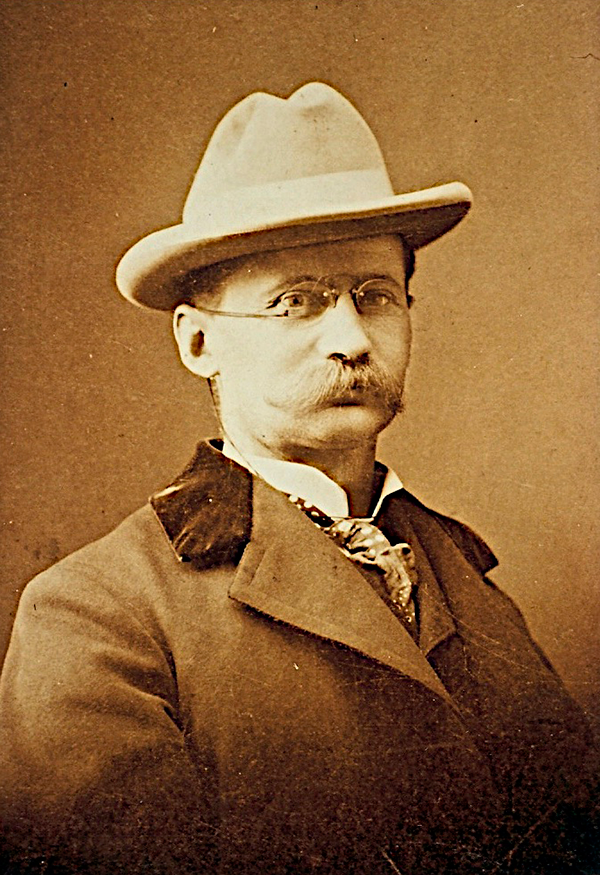 Sepia photographic portrait of Jens Jensen sporting glasses, a hat, a suit and a large mustache