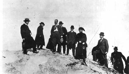 Stephen Mather stands atop a dune with Henry Cowles, Richard Leiber, Bess Sheehan, and others.
