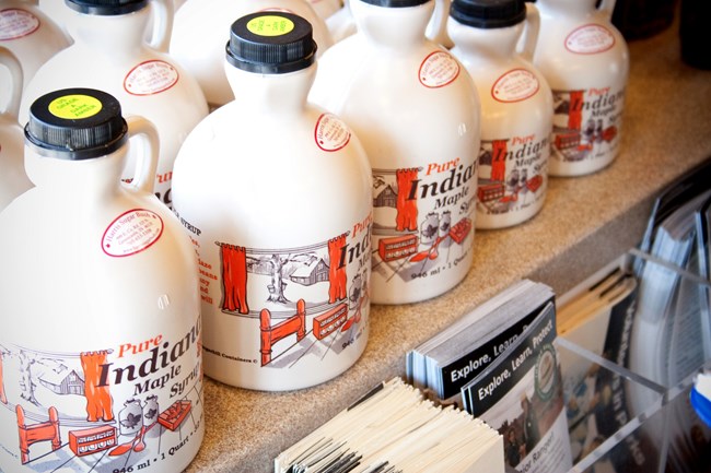 A row of containers holding Indiana maple syrup.